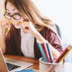Student at laptop biting pencil