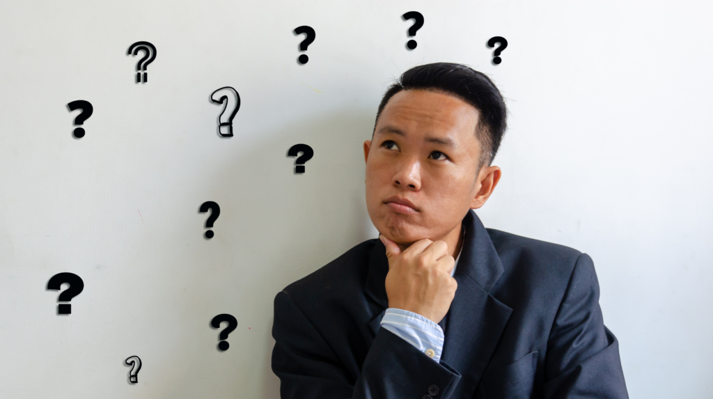 A man is leaning against a wall pondering if he should get into real estate with The Learning Team