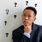 A man is leaning against a wall pondering if he should get into real estate with The Learning Team